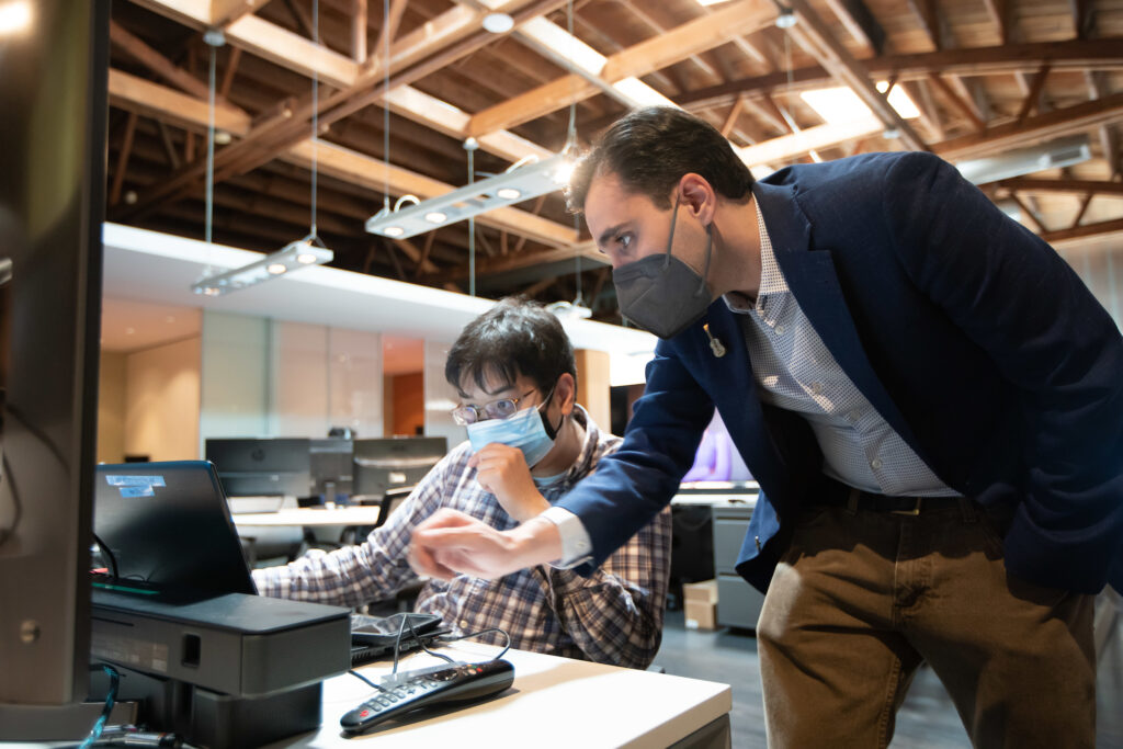 Maxwell Huffman helps a male employee working at a computer.