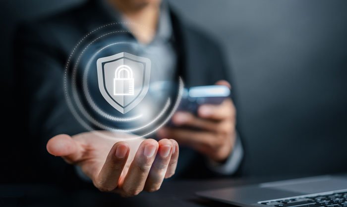 A lock and shield icon floats above an outstretched hand while the other hand holds a smartphone.