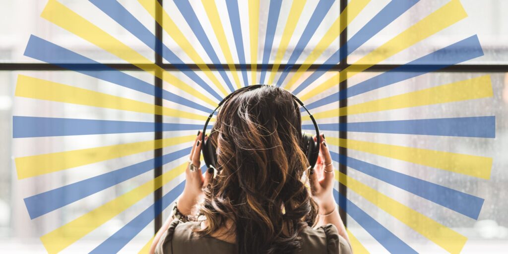 Professional woman with headphones looking out a large office window. A semi-transparent graphic burst of blue and yellow rays fan out around her.