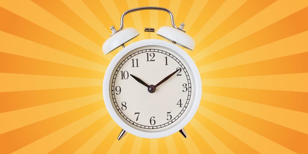 A black and white alarm clock against a yellow and orange burst graphic.